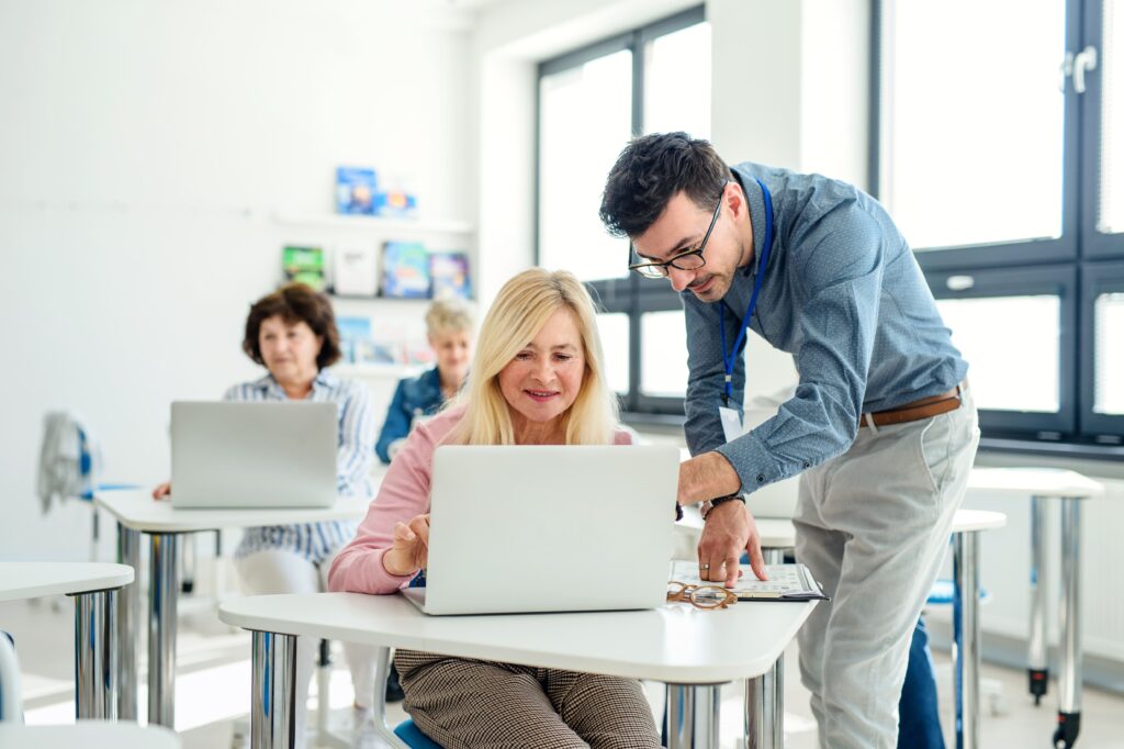 DOCENTE PARA CURSO "COMPETENCIAS DIGITALES AVANZADAS" 4 Un profesor ayudando a su alumna mientras señala algo en su portátil