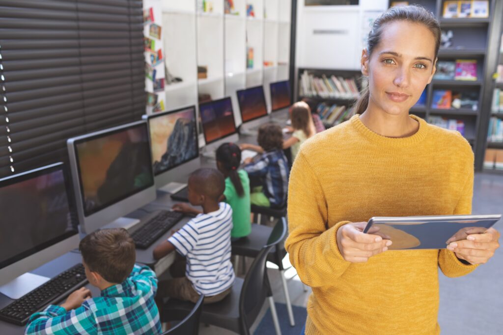 DOCENTE PARA CERTIFICADO EN SISTEMAS MICROINFORMÁTICOS 3 Una profesora con una tablet y sus alumnos trabajando en los ordenadores