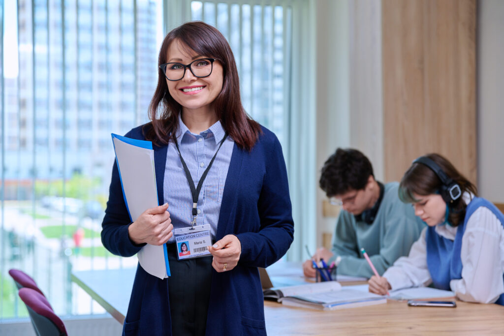 DOCENTE PARA MÓDULOS TRANSVERSALES 2 Una profesora con dos alumnos estudiando detrás de ella