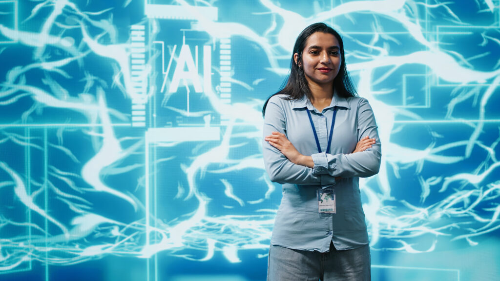 DOCENTE PARA CURSO "ESPECIALISTA EN INTELIGENCIA ARTIFICIAL" 2 Una mujer de pie con una pantalla detrás con contenido sobre IA