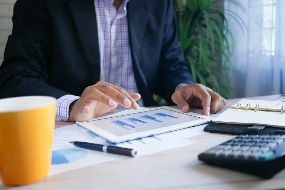 Persona revisando gráficos en una tableta junto a una calculadora